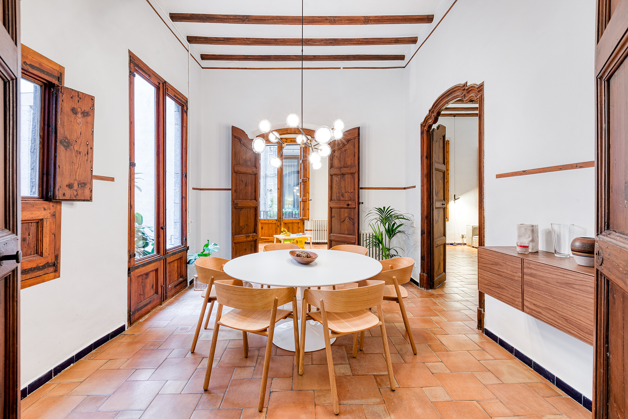 "Elegant round dining table in a historic 17th-century Barcelona vacation rental, seating 12+ guests—perfect for family gatherings, group dinners, and memorable evenings in El Born."